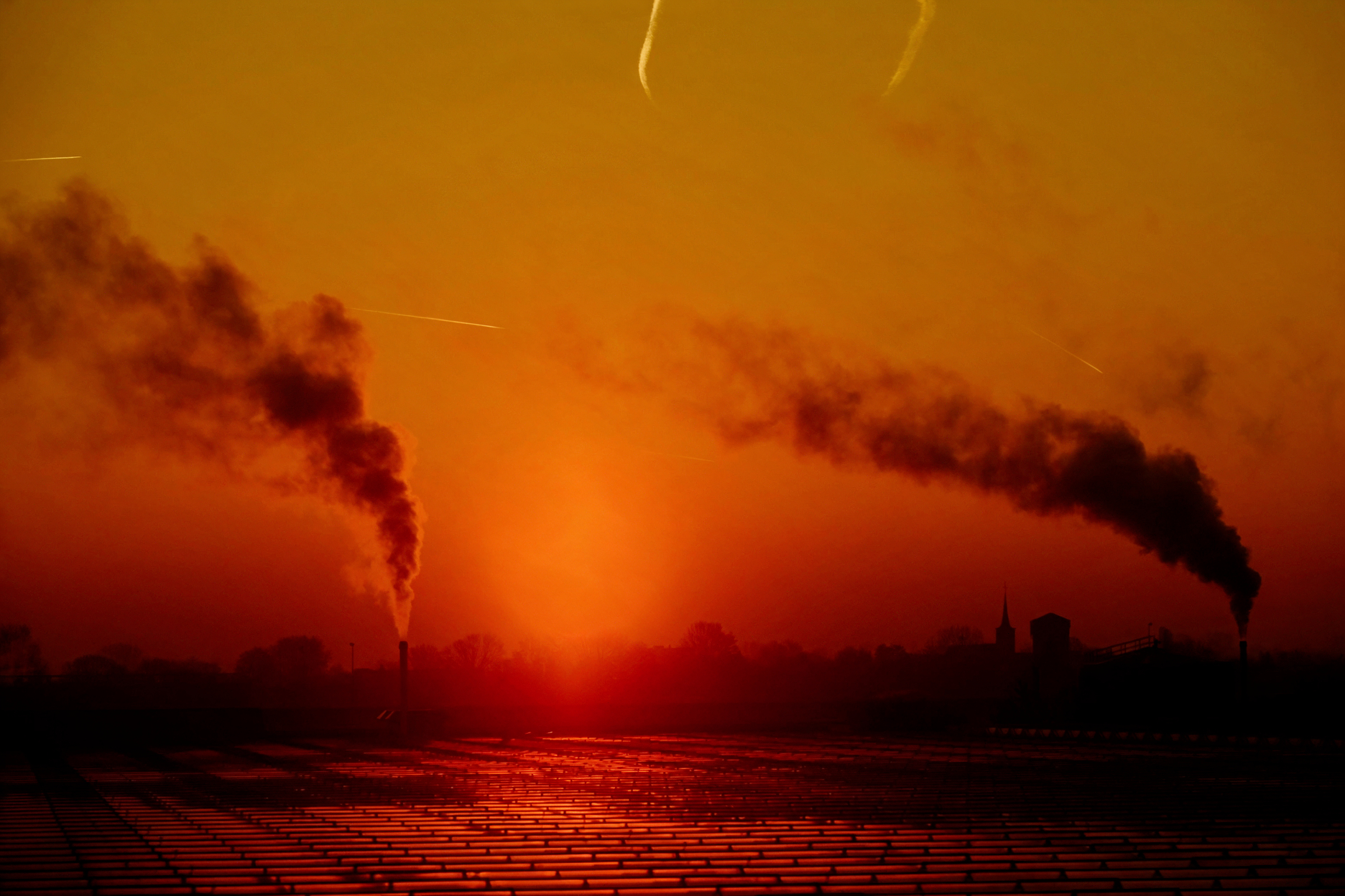 Heavy industrial factory with smoke and steam from chimneys at sunset